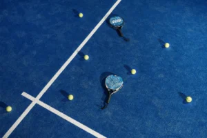 Raket dan bola padel di lapangan biru.