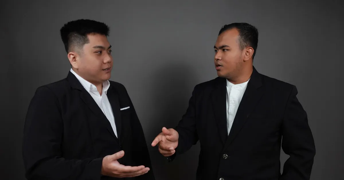 Dua pebisnis sedang berdiskusi mengenai persyaratan dan proses Pengusaha Kena Pajak (PKP) di ruang pertemuan